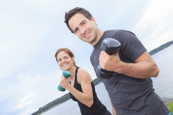 A Young, caucasian couple working out with dumbbells outside - Фото, зображення
