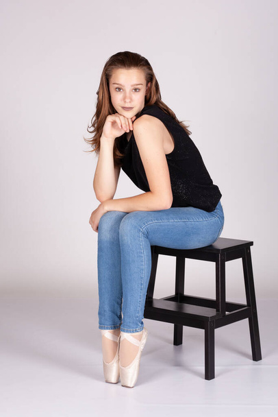 En Pointe resting on stool legs together coy expression looking at the camera hand to chin in a shrug en pointe Beautiful teen girl looking quizically with machiavellian tendencies Metaphor image for meme - Fotó, kép