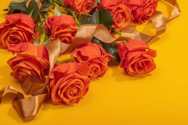 Bouquet of fresh bright roses on orange background. Romantic gift concept, greeting card. Valentines, Woman's or Mothers Day. Wedding, Anniversary, Birthday, flat lay, copy space - Foto, imagen