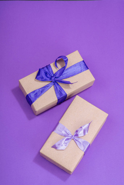 Zero waste gift concept. Wrapped in craft paper surprise box for Anniversary, Mothers or Valentines Day. Happy birthday greeting card, purple background, flat lay, top view - Photo, Image
