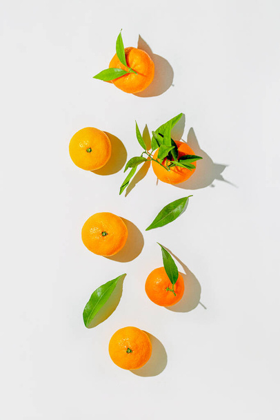 Creatieve stillevens compositie gemaakt van verse oranje mandarijnen op witte achtergrond met schaduw. Minimale stijl. Gezond voedsel concept. Zomer verfrissing thema. Bovenaanzicht - Foto, afbeelding