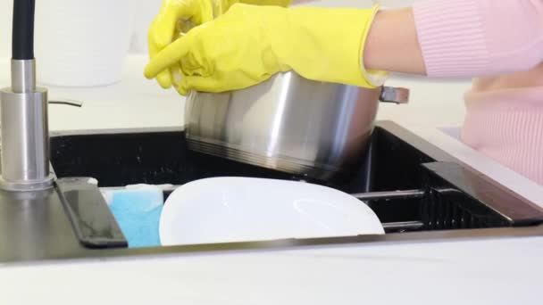Крупным планом женщины в перчатках мыли кастрюлю моющим средством. Уборка кухни. Чистота дома. Обычные женщины - Кадры, видео
