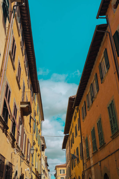 Pisa, Italia - 18. maaliskuuta 2023: Pysäköinti kukkulalla vanhassa kaupungissa. Kadulla on muinaisia rakennuksia Pisan keskustassa, Italiassa. Kuva historiallisen keskustan vanhojen rakennusten julkisivuista - Valokuva, kuva