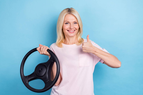 Portrait of satisfied woman straight hairdo wear white t-shirt hold steering wheel show like approve isolated on blue color background. - Foto, Bild