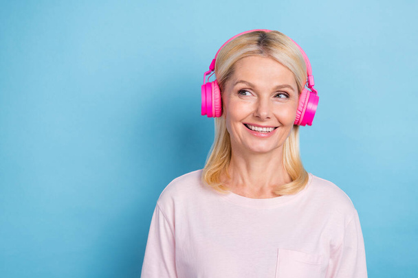 Photo of cute positive person toothy smile look empty space enjoy music earphones isolated on blue color background. - Fotó, kép