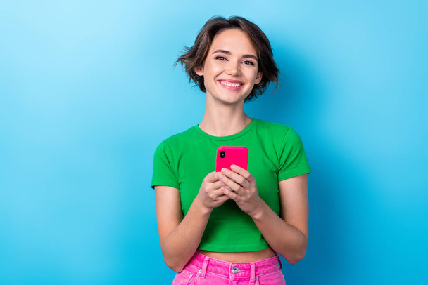 Photo of smiling optimistic satisfied blogger youngster lady hold smartphone chatting her boyfriend happy emotion isolated on cyan color background. - Fotó, kép