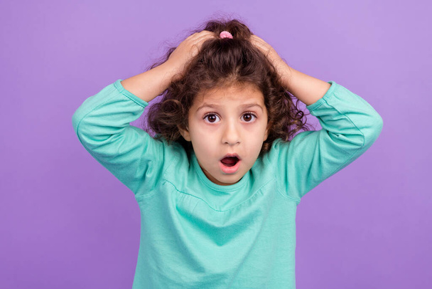 Photo of excited amazed small kid wear turquoise shirt arms head open mouth isolated purple color background. - Foto, Imagen