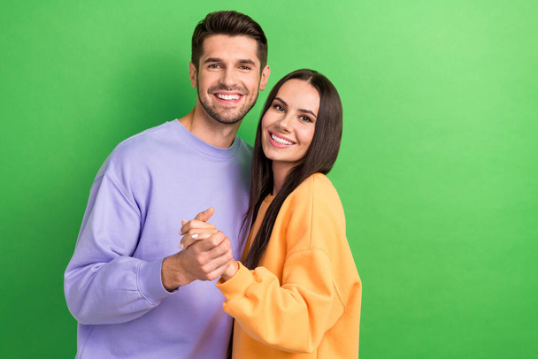 Photo of dreamy adorable boyfriend girlfriend wear sweatshirts embracing empty space isolated green color background. - Foto, imagen