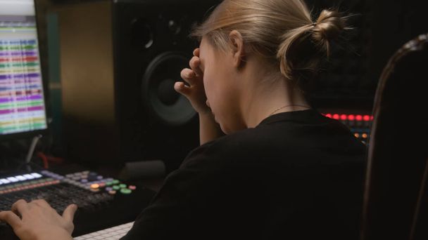 録音スタジオで経験豊富なオーディオエンジニアやプロデューサーの作品。女は新しい歌を作成するために混合コンソール及びデジタル可聴周波ワークステーションソフトウェアを使用する。PCモニターで音楽を録音するためのプログラム. - 写真・画像