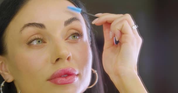 Reflection in the mirror of a beautiful brunette woman doing eyebrow correction. Slow motion 4k footage. - Footage, Video