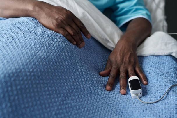Close-up do paciente checando oxigênio no sangue com oxímetro de pulso na mão enquanto estava deitado na cama na enfermaria - Foto, Imagem
