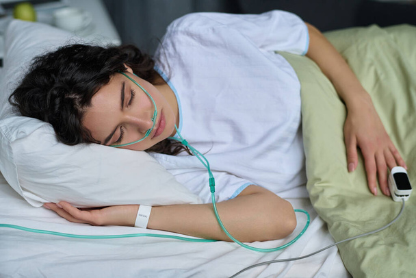 Młoda kobieta śpi z rurką tlenową w łóżku na oddziale szpitalnym - Zdjęcie, obraz