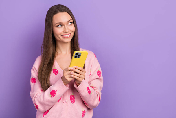 Photo of shiny dreamy lady dressed strawberry print cardigan texting gadget looking empty space isolated purple color background. - Foto, afbeelding
