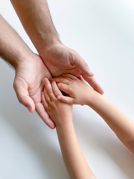 Un adulto y un niño mantienen sus manos juntas. Día del Padre. Un niño da una mano a un adulto. Concepto postal - Foto, Imagen