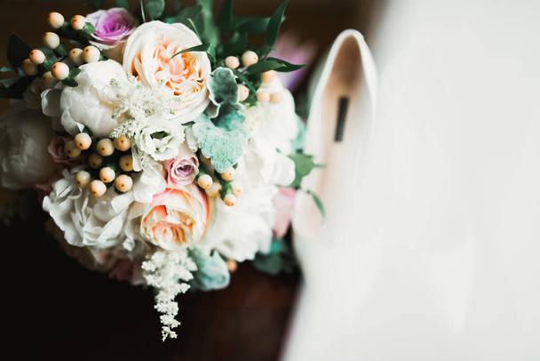 Brides wedding shoes with a bouquet with roses and other flowers. - Foto, afbeelding