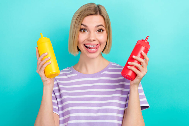 Portrait of positive good mood woman with stylish hairdo striped t-shirt hands hold sauce lick teeth isolated on teal color background. - Valokuva, kuva