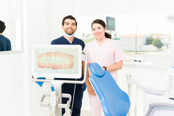 Zahnärztin und Zahnarzthelferin lächelnd bei Blickkontakt während kieferorthopädische Behandlung mit 3D-Modellierung für Smile Design - Foto, Bild