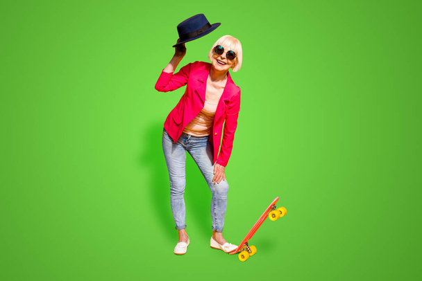 Full-body full-legh portrait of happy granny with a board for skating isolated on vivid yellow background. - Photo, image