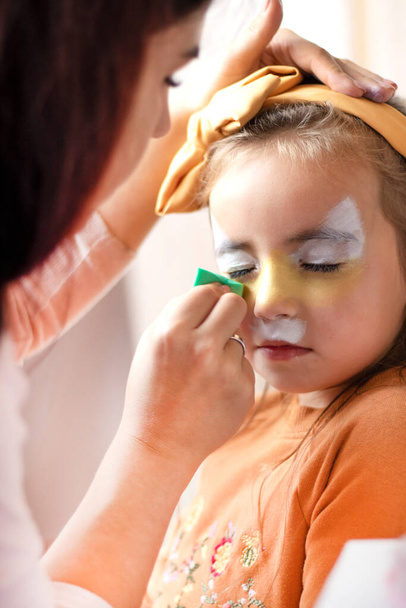kinderen make-up gezicht verf tekeningen Meisjes gezicht schilderen. Een klein meisje met een gezicht geschilderd op een verjaardagsfeestje. gesloten ogen. Hoge kwaliteit foto - Foto, afbeelding