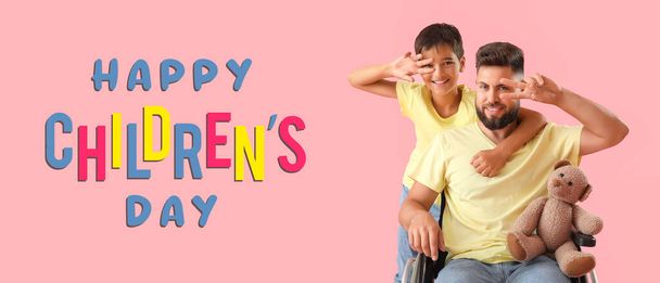 Kleiner Junge und sein Vater im Rollstuhl auf rosa Hintergrund. Glücklicher Kindertag - Foto, Bild