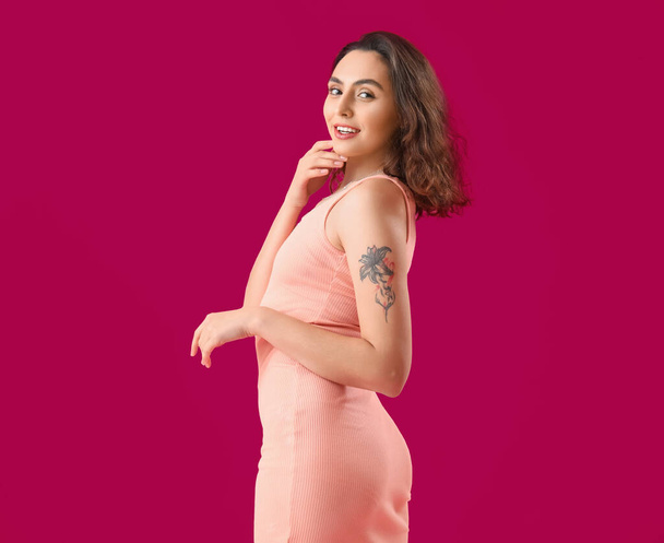 Aantrekkelijke jonge vrouw in jurk op roze achtergrond - Foto, afbeelding