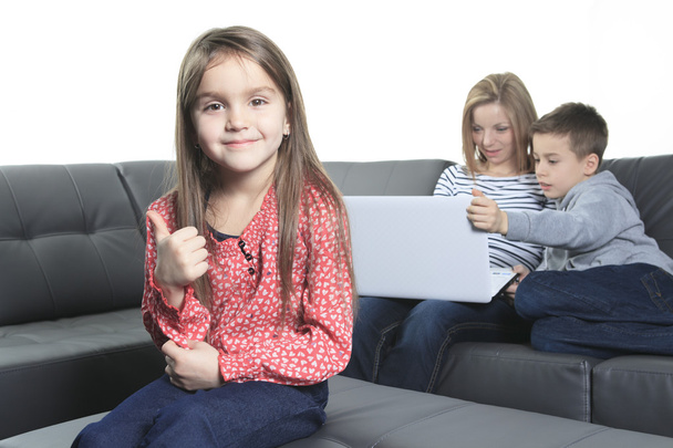 Bild einer freundlichen Familie, die auf dem Sofa sitzt und den Laptop betrachtet - Foto, Bild