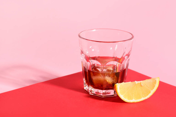 Glass of rum with ice cubes and lemon slice on colorful background - Foto, immagini