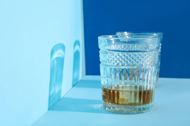 Glasses of rum with ice cubes on blue background - Foto, Imagen