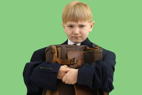 Funny little businessman in big jacket with briefcase on green background - Фото, зображення