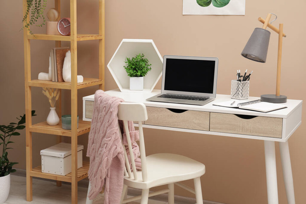 Cozy workplace with modern laptop on desk and comfortable chair at home - Zdjęcie, obraz
