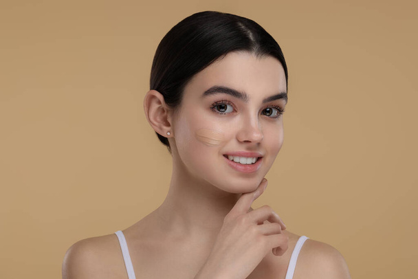 Teenage girl with swatch of foundation on face against beige background - Foto, Imagem