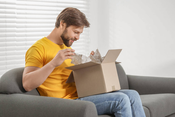 Happy man opening parcel at home. Internet shopping - Foto, immagini