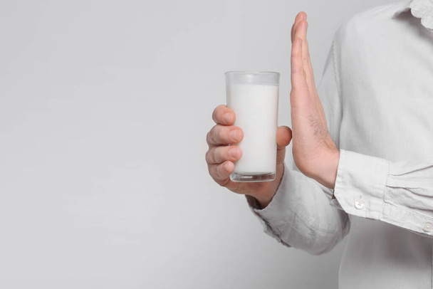 Man with glass of milk suffering from lactose intolerance on white background, closeup. Space for text - Valokuva, kuva