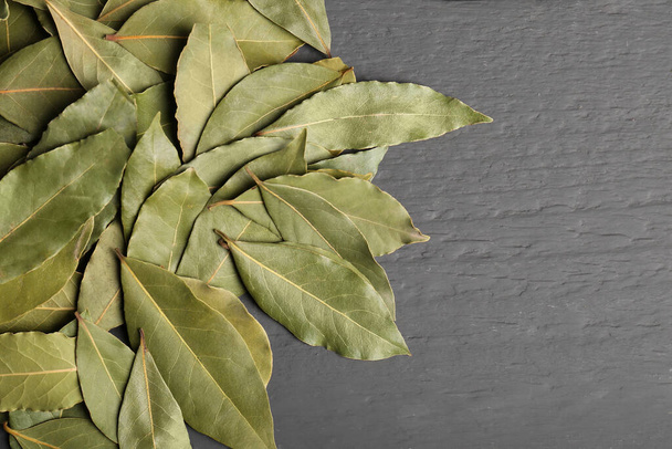 Pile of aromatic bay leaves on gray wooden table, top view. Space for text - Foto, Imagem
