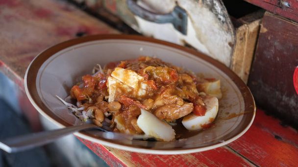 Tauge goreng ou germes de haricots frits est un plat végétarien salé indonésien fait de tauge sauté avec des tranches de tofu, gâteau de riz ketupat et jaune servi dans une sauce épicée à base d'oncom. - Photo, image