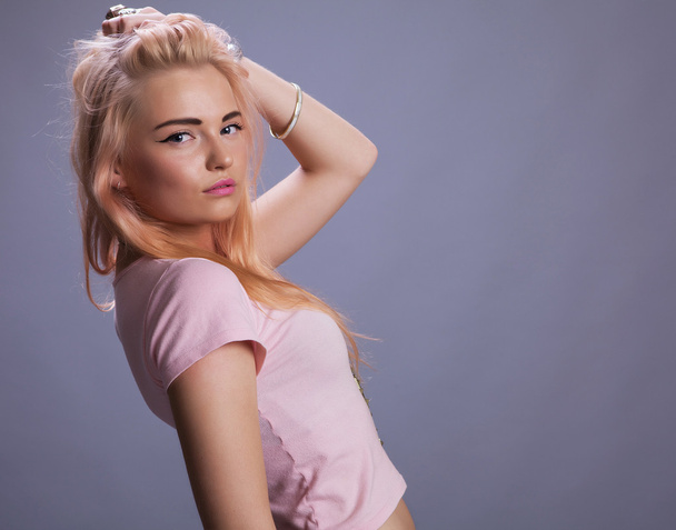 Blond girl in pink on studio gray background - Fotó, kép