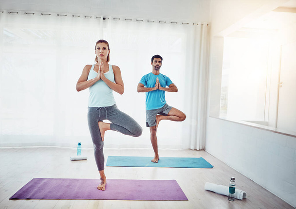 Aumenta la conexión que tienes con tu persona especial. una pareja practicando yoga en casa - Foto, Imagen