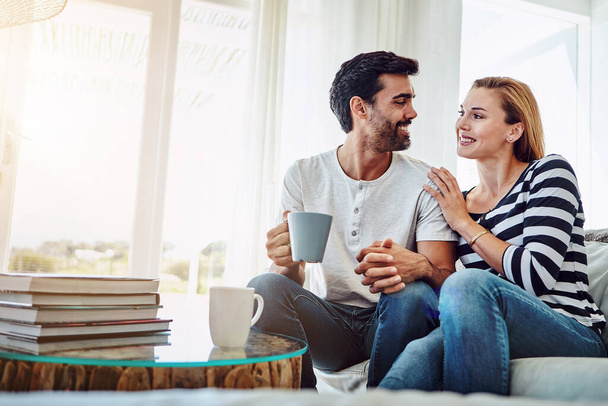 I love spending time with you. an affectionate young couple having coffee while relaxing on the sofa at home - Foto, Imagen