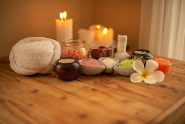 Beautiful spa composition with candles frangipani flower bowl with salt and herbal ball on wood table. - Photo, Image