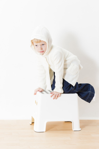 petite fille agenouillée portant un pull blanc
 - Photo, image