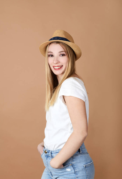 Portrait of pretty young woman with hat on beige background - Photo, image