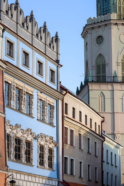 Lublin, Polonia - 23 de mayo de 2022: Torre Trinitaria, vista desde la Plaza de la Ciudad Vieja y casas de viviendas decorativas medievales. La torre tiene dos fachadas del mismo diseño, frente al casco antiguo y la Plaza de la Catedral. - Foto, imagen