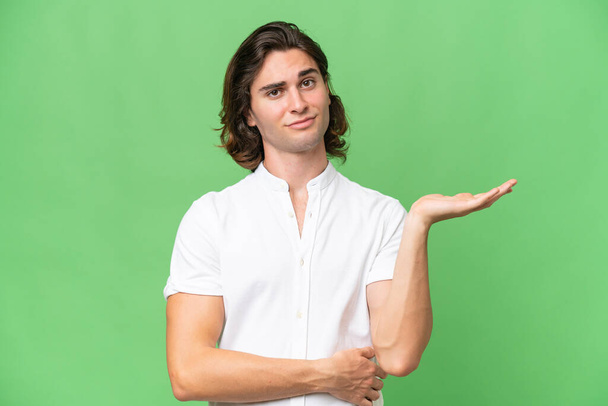 Young caucasian man isolated on green chroma background having doubts - Photo, Image