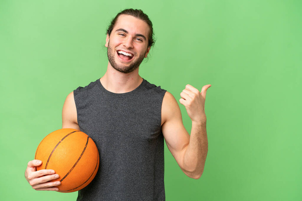 プロダクトを提示するために側面を指す隔離された背景の上の若いバスケットボール選手の男 - 写真・画像
