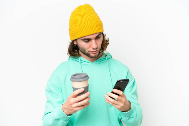 Молодий красивий чоловік ізольований на білому хромовому фоні, тримає каву, щоб забрати і мобільний
 - Фото, зображення