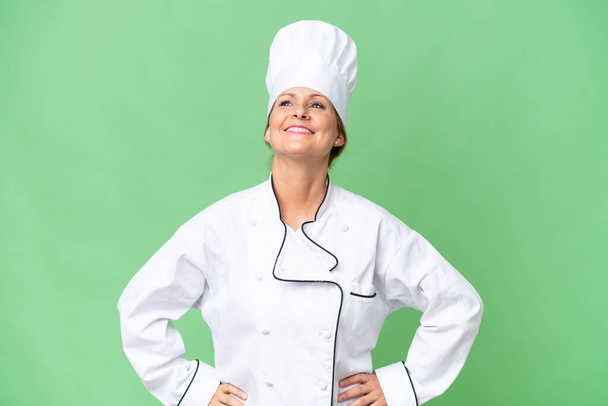 Middle-aged chef woman over isolated background posing with arms at hip and smiling - Photo, Image