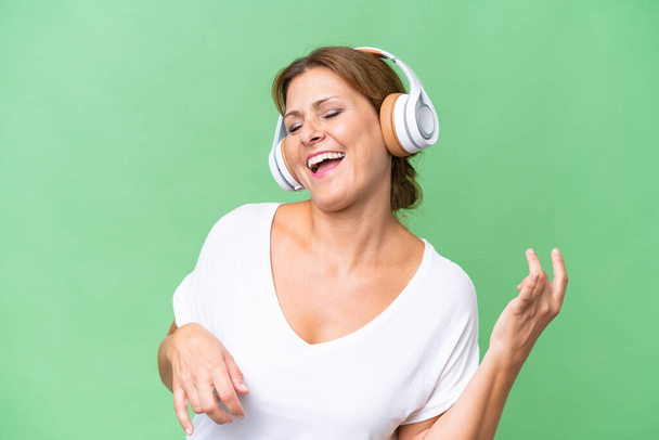 Middle-aged caucasian woman over isolated background listening music and doing guitar gesture - Fotoğraf, Görsel