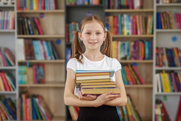 Dítě kupuje knihy v knihkupectví pro učení nebo čtení. Dívka vybírá knihu ve školní knihovně. Výhody každodenního čtení. - Fotografie, Obrázek