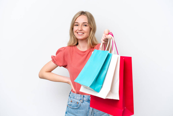 Young English woman isolated on white background holding shopping bags and giving them to someone - Foto, afbeelding