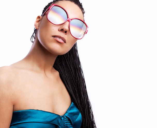 Beautiful fashion mulatto woman wearing sunglasses over a white background. - Фото, изображение